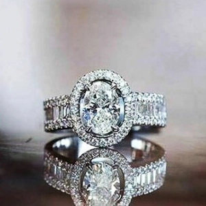 Detailaufnahme von Smaragdring mit Halo und mit Diamanten besetzter breiter Ringschiene