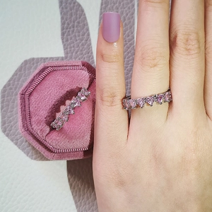 Minimalist silver ring featuring a full circle of pink heart-cut gems and velvet box