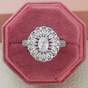 Detailed close-up of a luxury silver sunburst ring with oval crystal in a pink velvet box