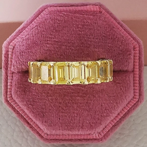 Detaillierte Draufsicht des Goldrings mit sieben gelben Smaragdschliff-Steinen in rosa Etui