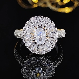 Luxury oval cut ring with marquise halo and pavé setting on black reflective surface