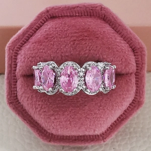 Makroaufnahme eines Silberrings mit fünf rosa Edelsteinen und Diamanten in einer Box
