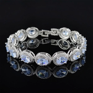 Elegante pulsera de plata con piedras preciosas azul claro sobre superficie negra reflectante