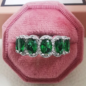 Detaillierte Makroansicht des Rings mit fünf ovalen grünen Edelsteinen in rosa Samtbox