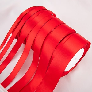 Detailed view of red polyester satin ribbons in various widths on white spools