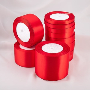 Detailed view of glossy red satin ribbon rolls in various widths for gift wrapping