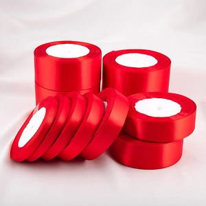 Detailed close-up of multiple widths of red polyester satin ribbon rolls for gift wrapping