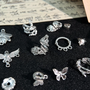 Dettaglio di ciondoli vintage in lega d'argento con motivi di rose, serpenti e farfalle