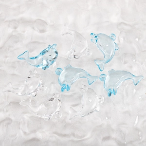 Close-up of translucent blue dolphin charms on textured frosted glass for DIY jewelry making
