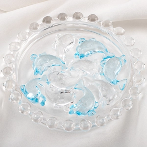 Detailed view of blue and clear resin dolphin charms for DIY jewelry on white satin