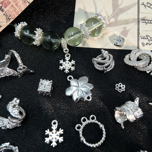 Dettaglio macro di ciondoli in lega d'argento per gioielli fai-da-te con perle verdi e fiori