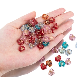Hand holding acrylic maple leaf beads with gold veins for DIY jewelry making