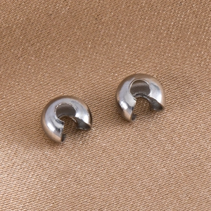 Macro shot of silver metal half-moon jewelry connectors on brown satin backdrop