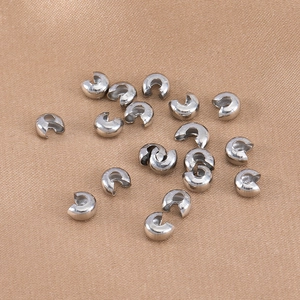 Detail view of 4mm silver crescent bead covers on brown satin fabric for DIY jewelry