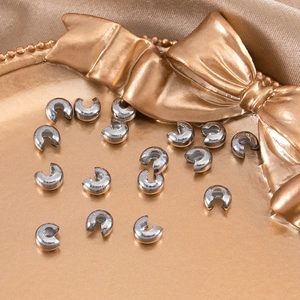 Macro shot of 4mm silver crescent bead covers on a decorative tray for DIY jewelry