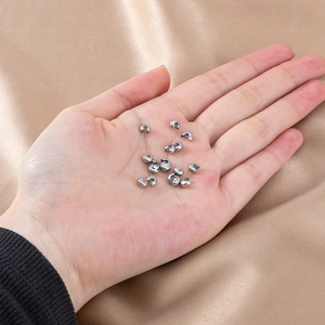 Micro shot of 4mm silver crescent bead crimps for jewelry making held in hand