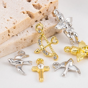 Detail of alloy Cupid arrow and cross pendants with inlaid rhinestones for DIY jewelry