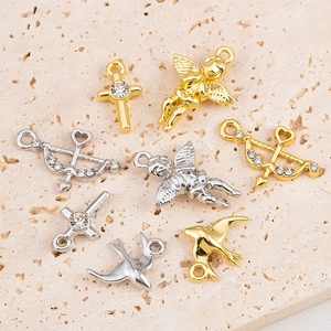 Macro view of gold and silver alloy charms featuring cross and cupid motifs for DIY jewelry