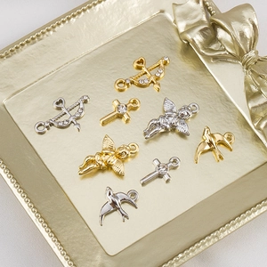 Detailed macro of gold and silver alloy Cupid arrow and cross charms with rhinestones