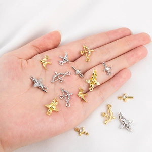 Golden and silver Cupid arrow and cross charms held in hand for DIY jewelry making