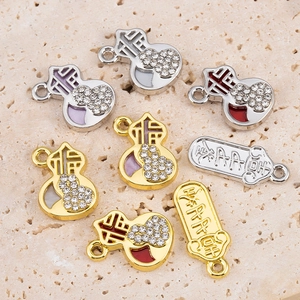 Detailed macro view of alloy gourd charms with inset rhinestones and red enamel for DIY jewelry