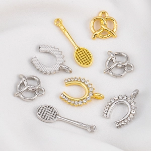 Détail de breloques DIY avec raquettes de tennis et formes de bretzel en or et en argent