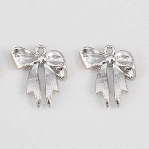 Gros plan de pendentifs nœuds argentés avec textures verticales et boucles en métal pour bijoux