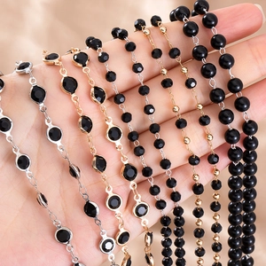 Detailed view of assorted black beaded chains and faceted stone bracelets held in hand