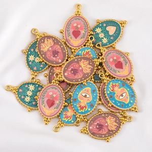 Detailed macro view of vintage eye and heart enamel charms with gold beaded edges