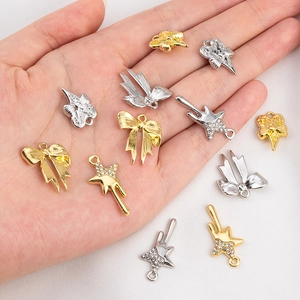Détail de pendentifs DIY dorés et argentés avec strass et formes d'étoiles et cœurs