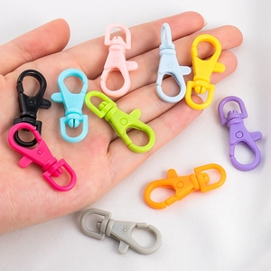 Colorful plastic lobster clasps for DIY keychains held in palm to show variety and size