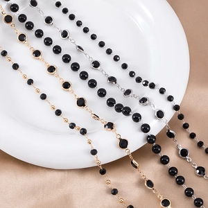 Detail of gold and silver chains with black beads on champagne silk fabric background