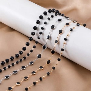 Detailed shot of black beads and faceted gems on gold and silver chain link accessories