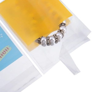 Detalle de bolsas transparentes para joyas con tarjetas de cartón amarillas y azules