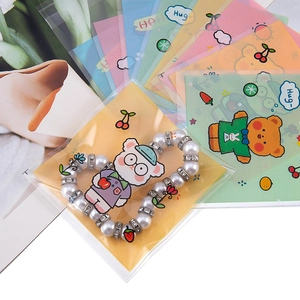 Detalle de pulsera de perlas en bolsa de embalaje transparente con patrón de oso