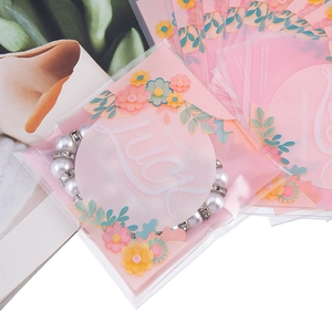 Sacchetto regalo rosa Lucky con bracciale di perle mostrato su sfondo di rivista