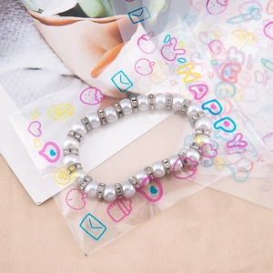 Elegante witte parelarmband met strass-tussenstukken in een decoratieve cadeauverpakking