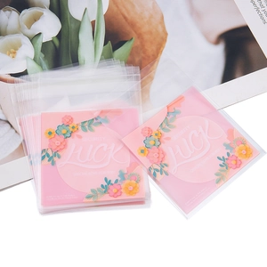 Dettaglio di sacchetti regalo floreali rosa con scritte LUCK per gioielli e dolci