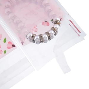 Dettaglio di un bracciale di perle in un sacchetto floreale rosa con finitura opaca
