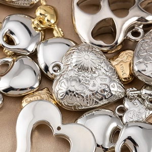 Macro di ciondoli a cuore oro e argento con trame floreali e incisioni su raso marrone