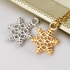 Vista macro di ciondoli a fiocco di neve con design esagonale traforato in oro e argento