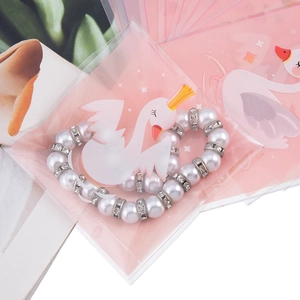 Dettaglio bracciale di perle con distanziatori in strass e confezione rosa con cigno