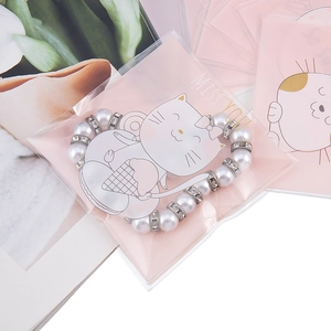 Dettaglio del braccialetto di perle e strass con confezione regalo a tema gatto rosa