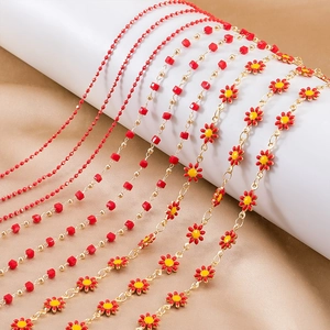 Detail of red enamel daisy and bead jewelry chains on a gold-plated display base