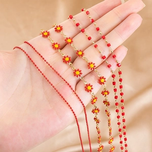 Detailed close-up of red enamel daisy sunflower and copper beaded chains for DIY jewelry