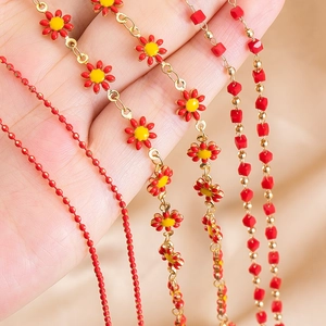 Red enamel flower charms and faceted bead necklaces on golden copper chain strands