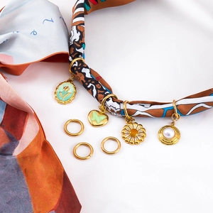 Detail van DIY sieraden hangers set met tulpen en madeliefjes op een zijden sjaal