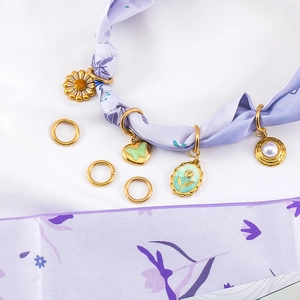 Detail van florale emaille hangers en gouden ringen op een zijden lint met bloemen
