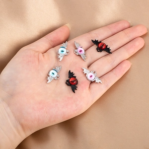 Macro shot of gothic bat wings devil eye charms in silver and black metal finishes