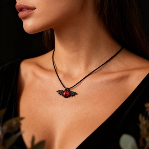 Gothic bat pendant necklace with a red evil eye and black woven chain on model